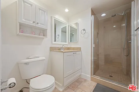 a bathroom with a granite countertop sink a toilet a mirror and shower