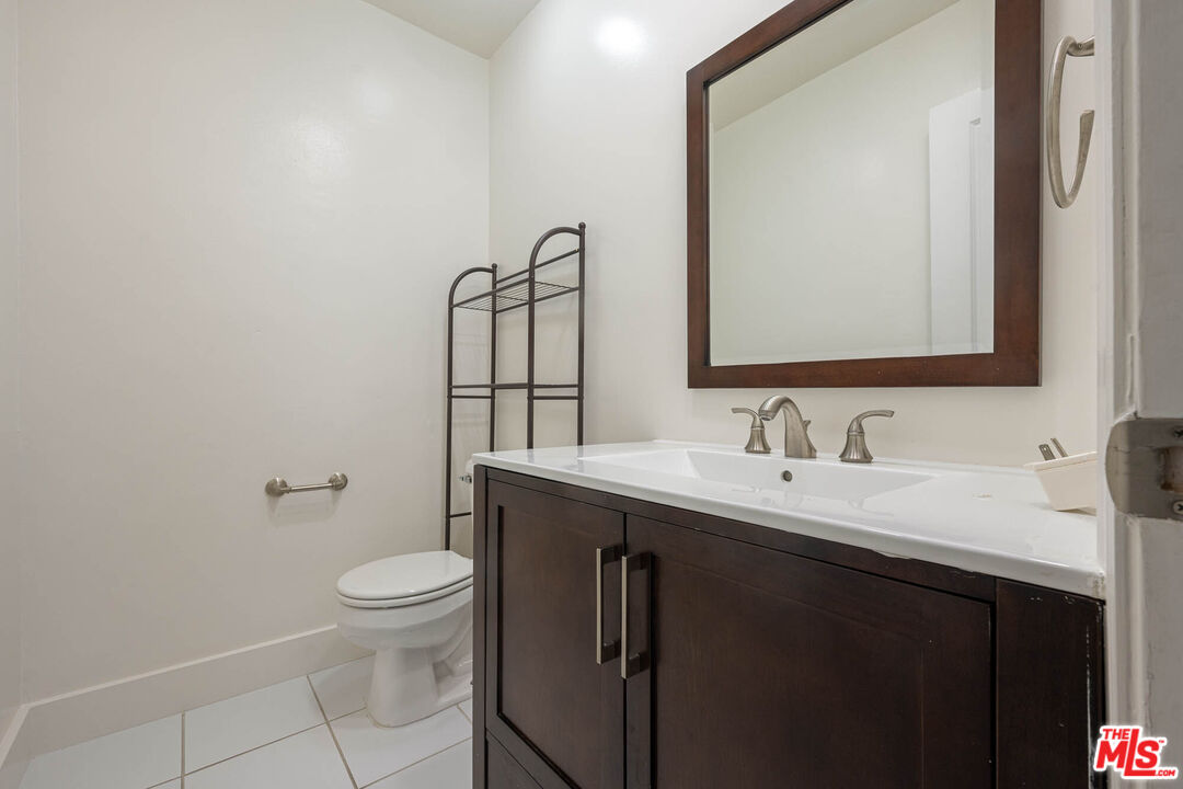 1515 South Beverly Drive, Unit 201 Los Angeles, CA 90035 - Photo 18 of 22 a bathroom with a granite countertop toilet sink mirror and