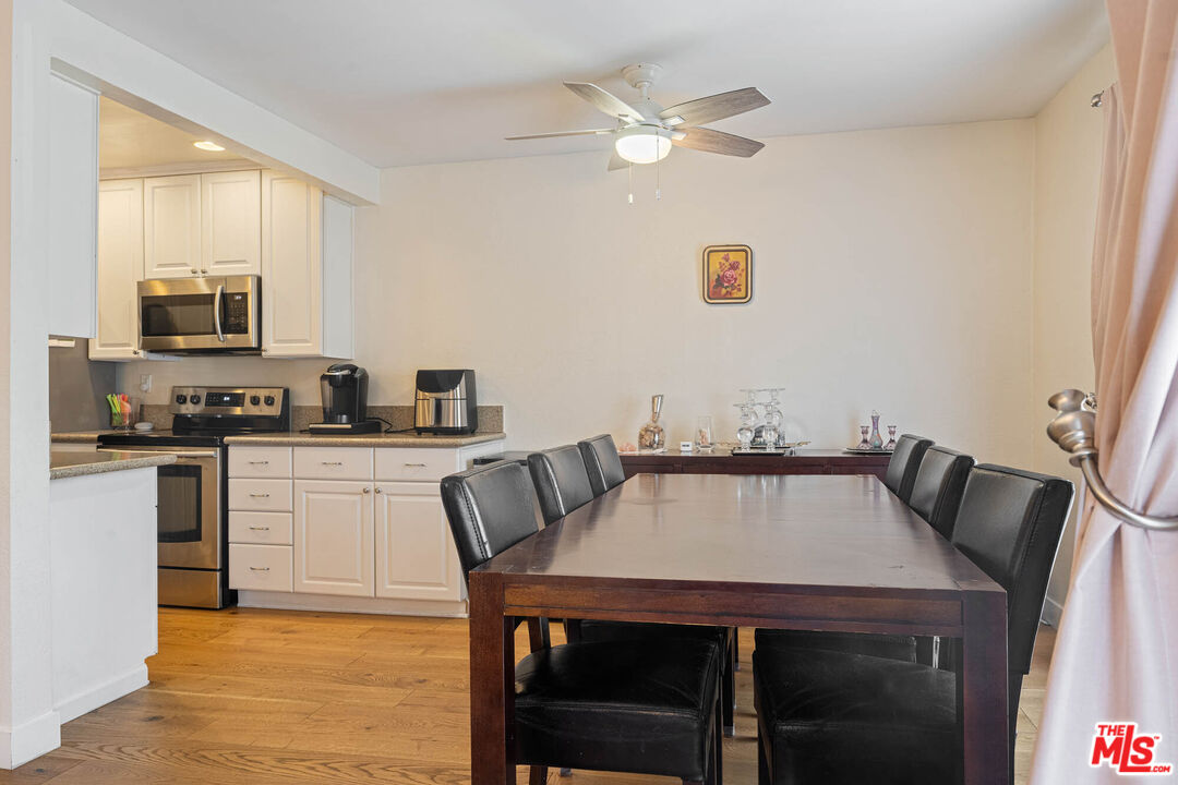 1515 South Beverly Drive, Unit 201 Los Angeles, CA 90035 - Photo 7 of 22 a kitchen with a table chairs a sink dishwasher stove and microwave with wooden floor