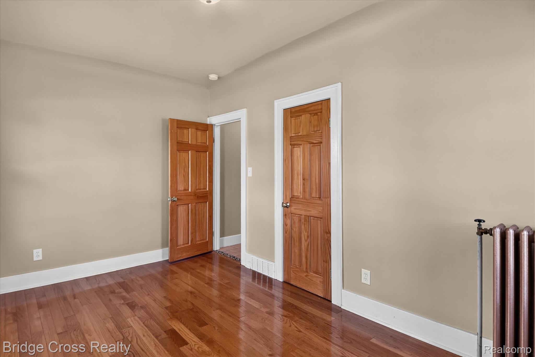 285 East Long Lake Road Troy, MI 48085 - Photo 29 of 49 Hardwood flooring, two paneled wood doors, and a cast iron radiator
