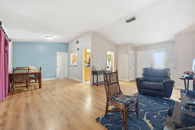 a living room with furniture and a dining table with wooden floor