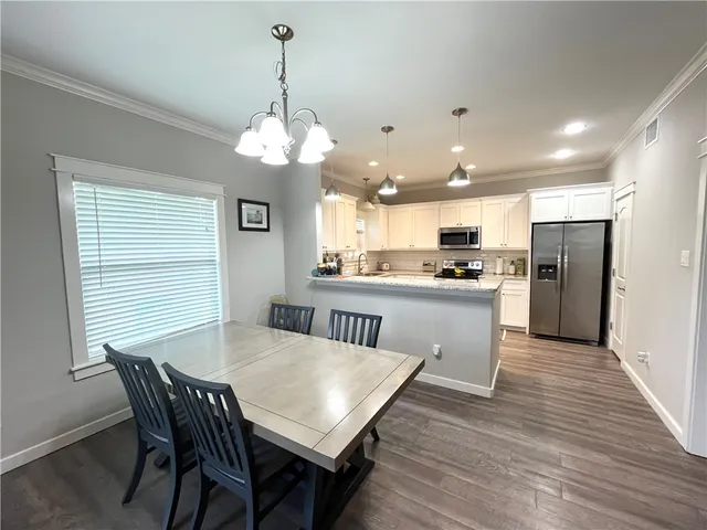 a kitchen with stainless steel appliances granite countertop a dining table chairs refrigerator and a window