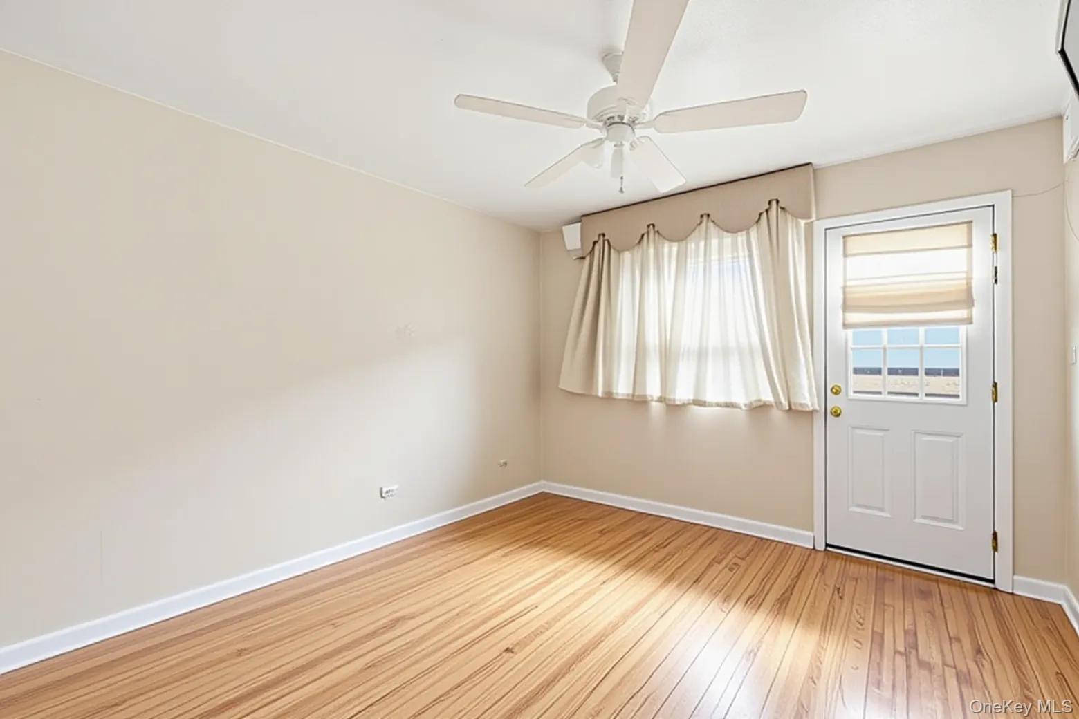 49-12 111th Street Queens, NY 11368 - Photo 14 of 31 an empty room with wooden floor fan and windows