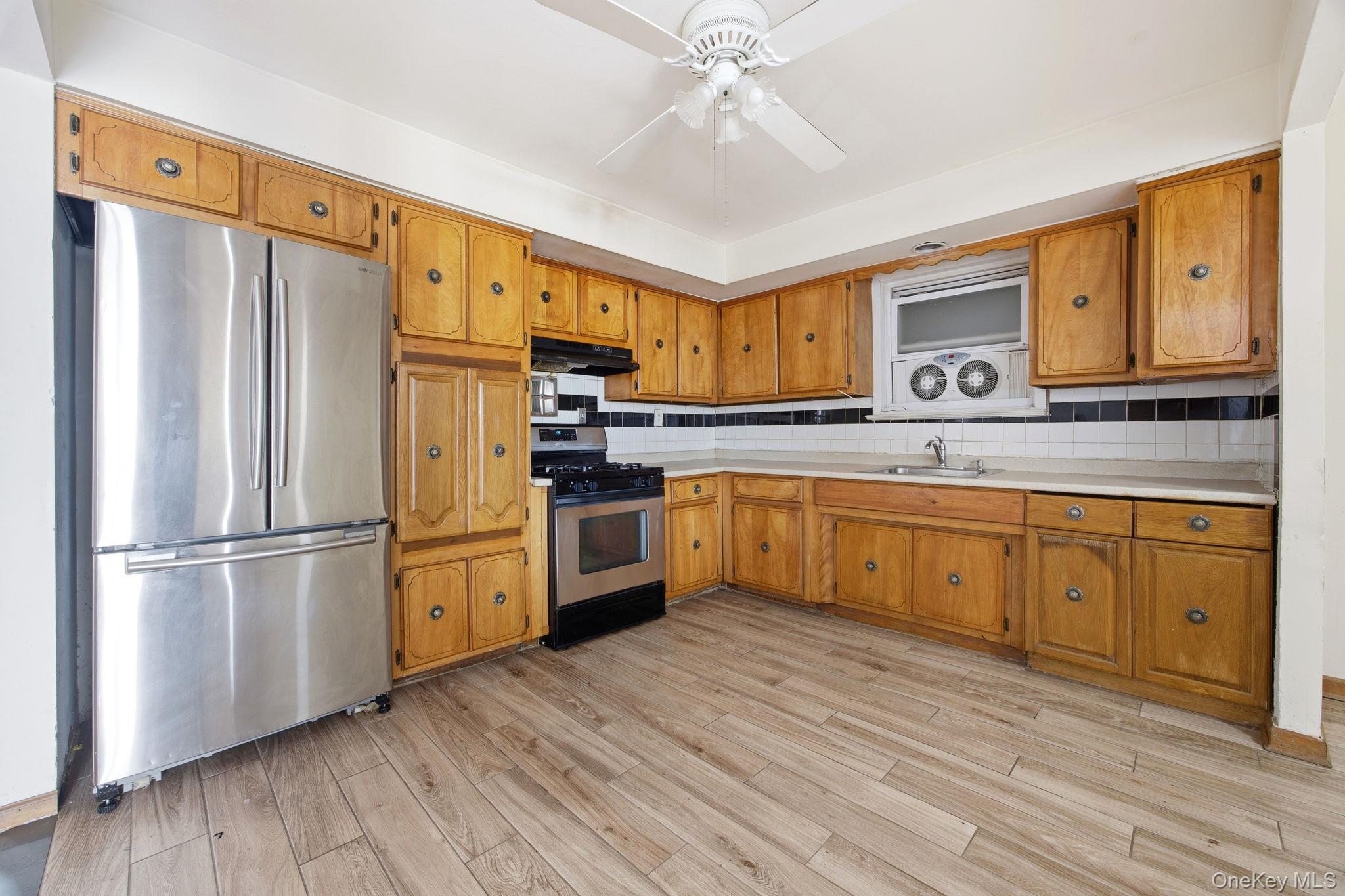 49-12 111th Street Queens, NY 11368 - Photo 15 of 31 a kitchen with stainless steel appliances a refrigerator sink and cabinets
