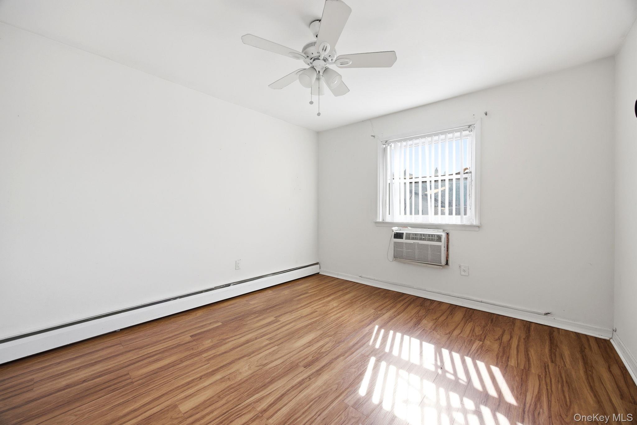 49-12 111th Street Queens, NY 11368 - Photo 21 of 31 an empty room with wooden floor chandelier fan and windows