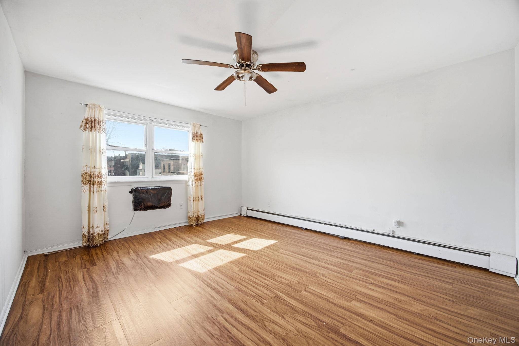 49-12 111th Street Queens, NY 11368 - Photo 23 of 31 a view of a livingroom with wooden floor and a ceiling fan