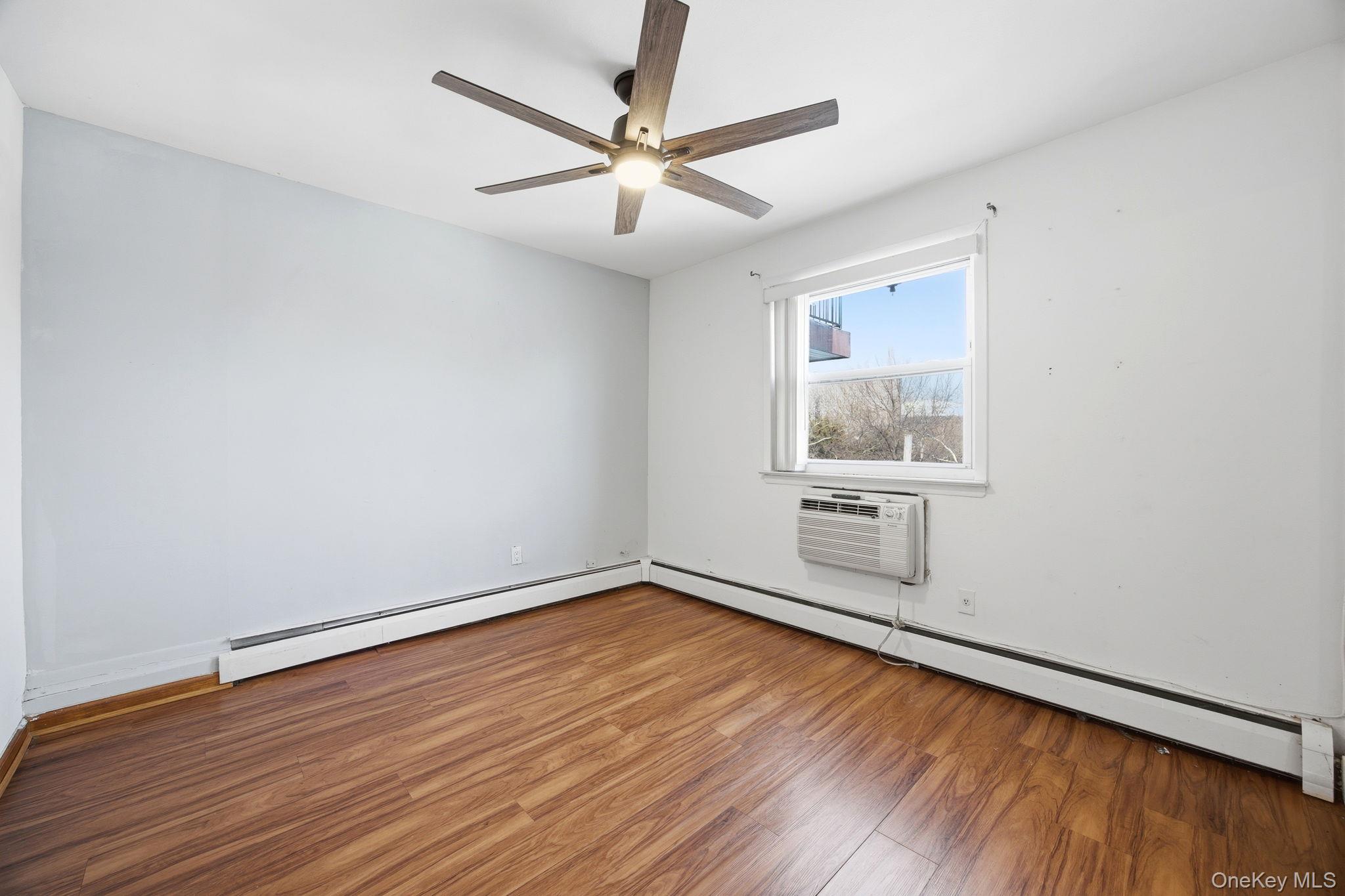 49-12 111th Street Queens, NY 11368 - Photo 26 of 31 an empty room with wooden floor chandelier fan and windows