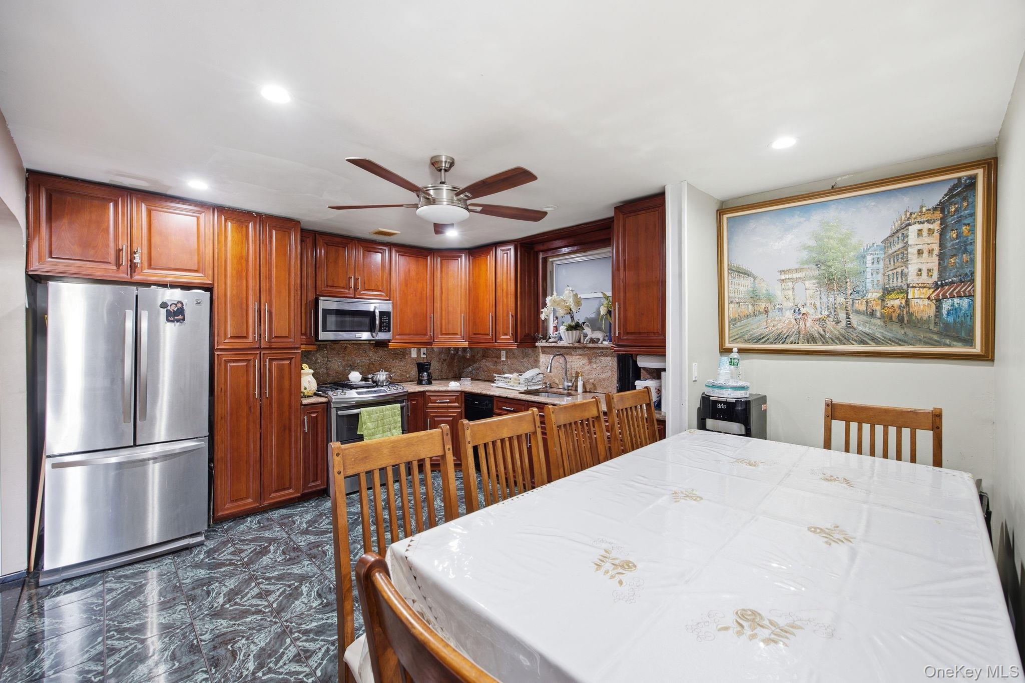 49-12 111th Street Queens, NY 11368 - Photo 6 of 31 a kitchen with stainless steel appliances granite countertop a refrigerator a sink dishwasher a stove and a dining table with wooden floor