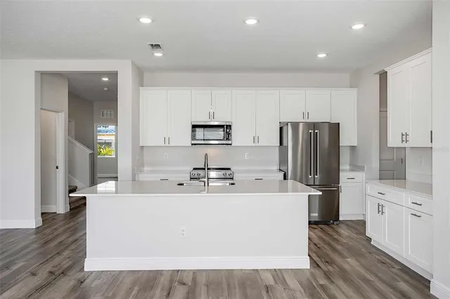 a kitchen with stainless steel appliances a refrigerator sink and white cabinets