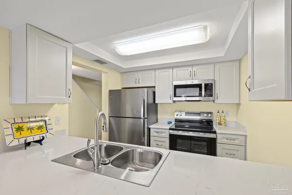 a kitchen with a sink a counter top space and living room area