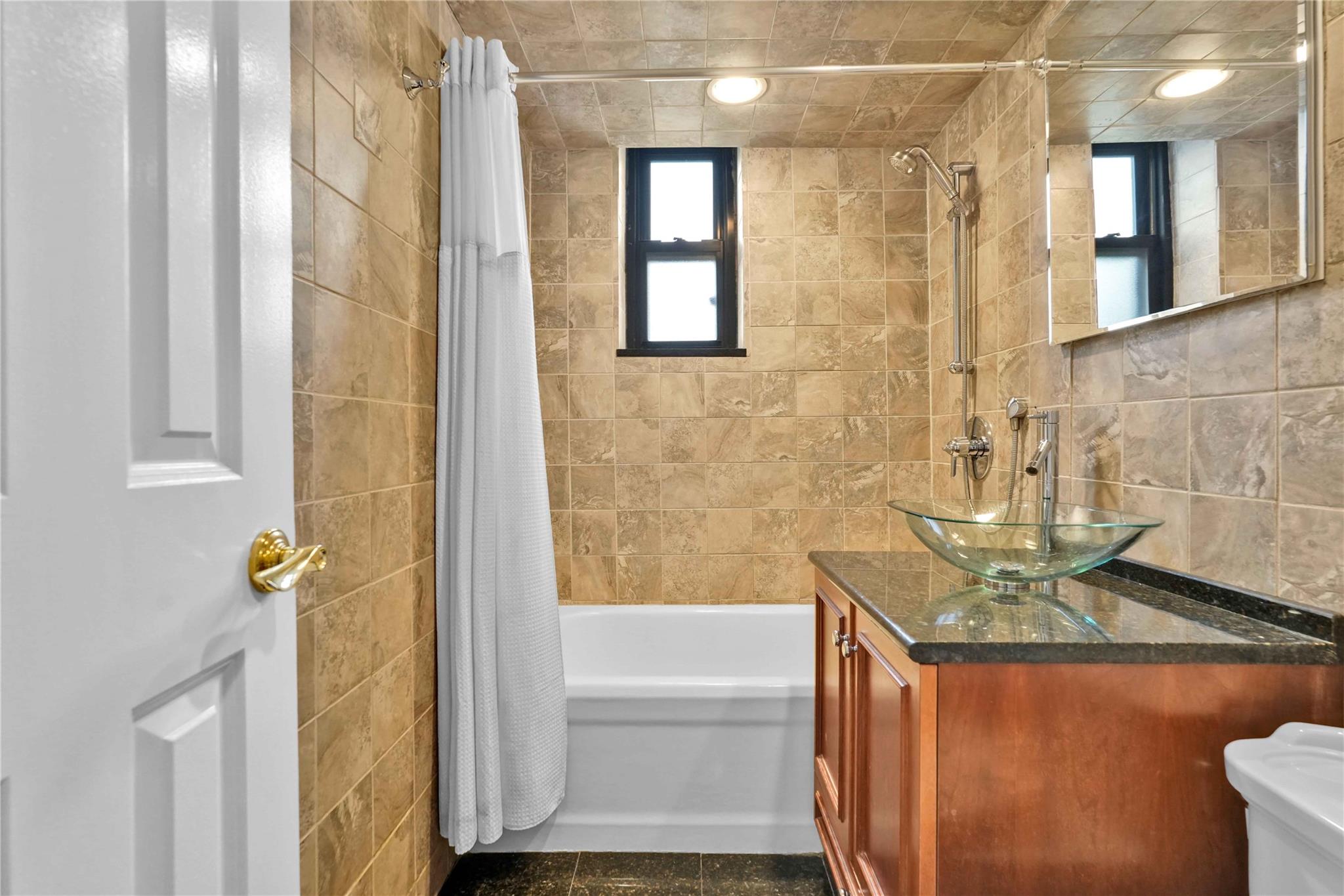 21-40 78th Street, Unit 2 Queens, NY 11370 - Photo 8 of 11 a bathroom with a granite countertop sink a toilet and bathtub