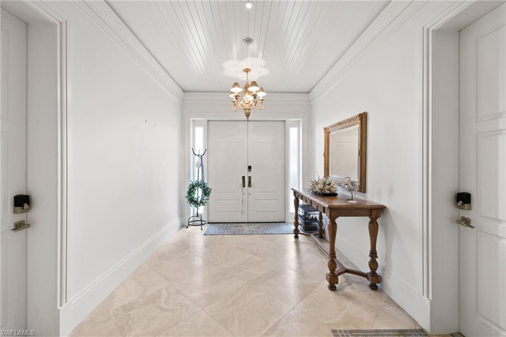 40 32nd Avenue South Naples, FL 34102 - Photo 12 of 49 Foyer entrance featuring a chandelier, ornamental molding, and light tile patterned floors