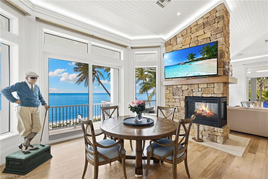 40 32nd Avenue South Naples, FL 34102 - Photo 21 of 49 Dining area featuring a stone fireplace, hardwood / wood-style floors, vaulted ceiling, and wood ceiling