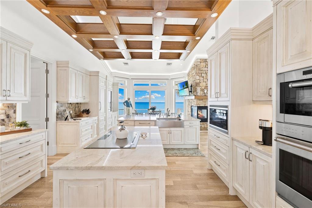 40 32nd Avenue South Naples, FL 34102 - Photo 23 of 49 Kitchen featuring coffered ceiling, black appliances, a kitchen island, beamed ceiling, and light wood-style floors