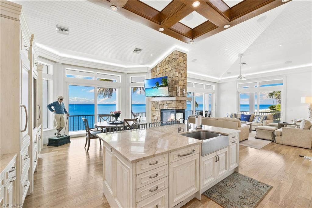 40 32nd Avenue South Naples, FL 34102 - Photo 48 of 49 Kitchen featuring light stone countertops, coffered ceiling, open floor plan, a stone fireplace, and beamed ceiling