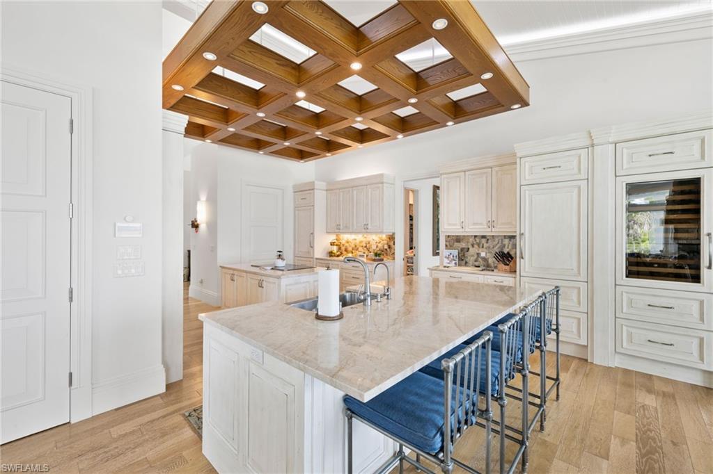 40 32nd Avenue South Naples, FL 34102 - Photo 24 of 49 Kitchen with coffered ceiling, a breakfast bar, backsplash, light wood-style flooring, and beam ceiling