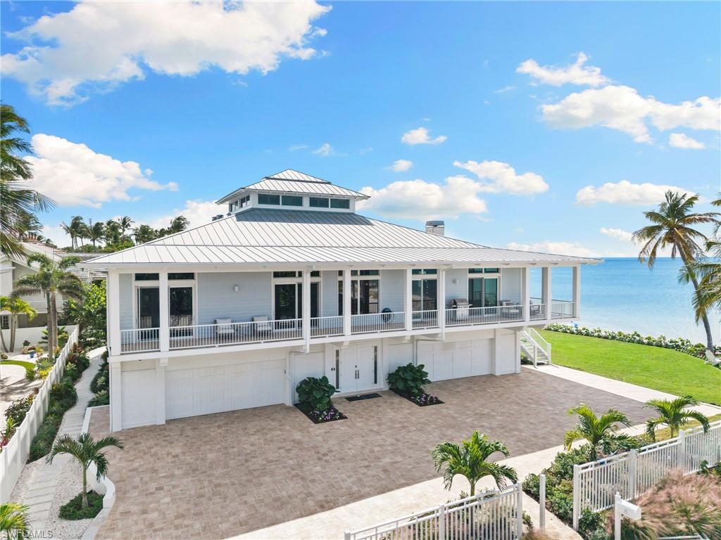 40 32nd Avenue South Naples, FL 34102 - Photo 3 of 49 Raised beach house featuring a water view, a standing seam roof, a fenced front yard, a garage, and decorative driveway