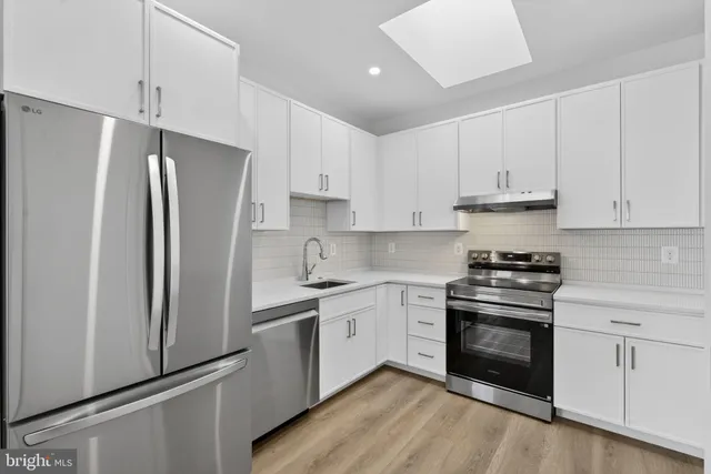a kitchen with white cabinets and stainless steel appliances