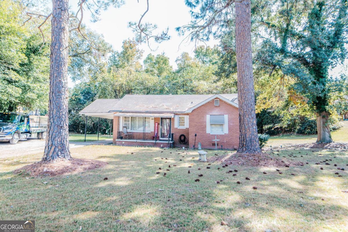 a view of a house with a yard and large tree