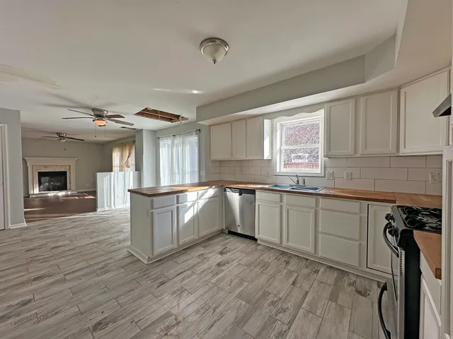 a large kitchen with granite countertop a large counter top space a sink stainless steel appliances and cabinets