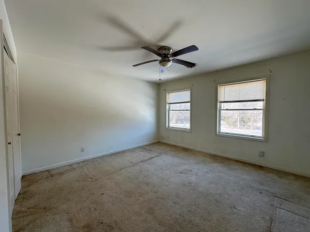 an empty room with windows and fan
