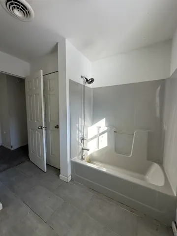 an empty room with windows and ceiling fan