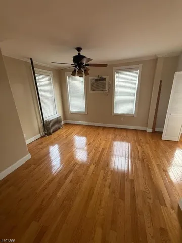 a view of empty room with wooden floor and fan