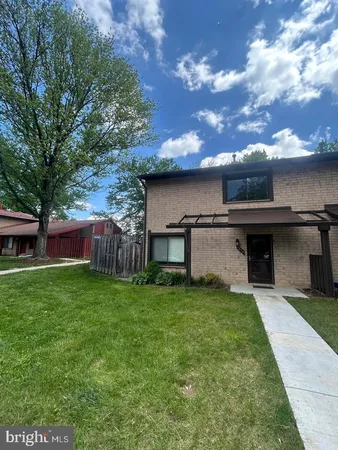 a view of a house with a yard and a large tree