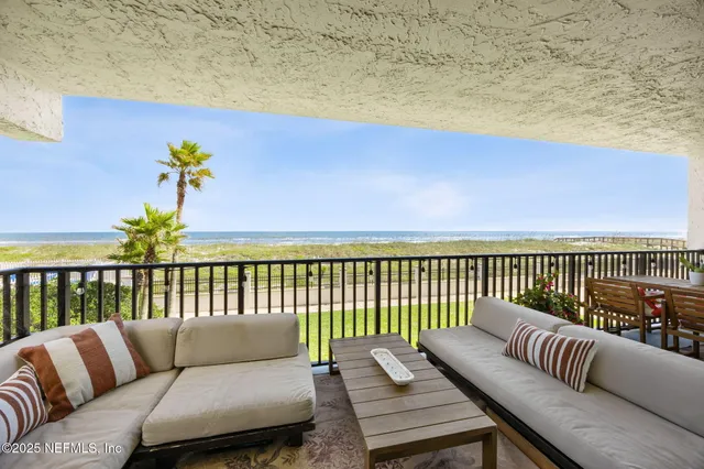 a front view of a building with glass windows and plants