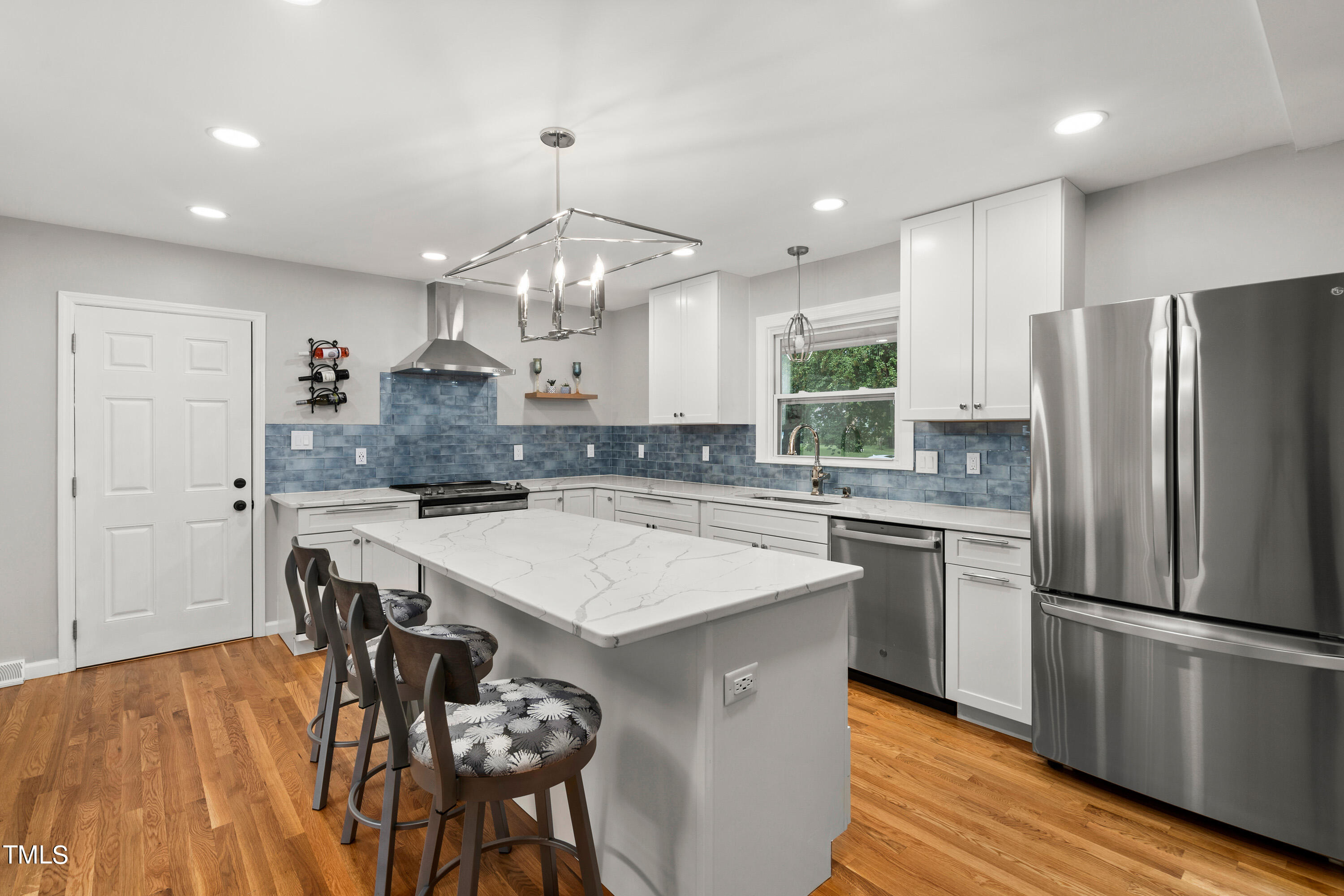 4817 Latimer Road Raleigh, NC 27609 - Photo 3 of 45 a kitchen with kitchen island a dining table chairs refrigerator and microwave