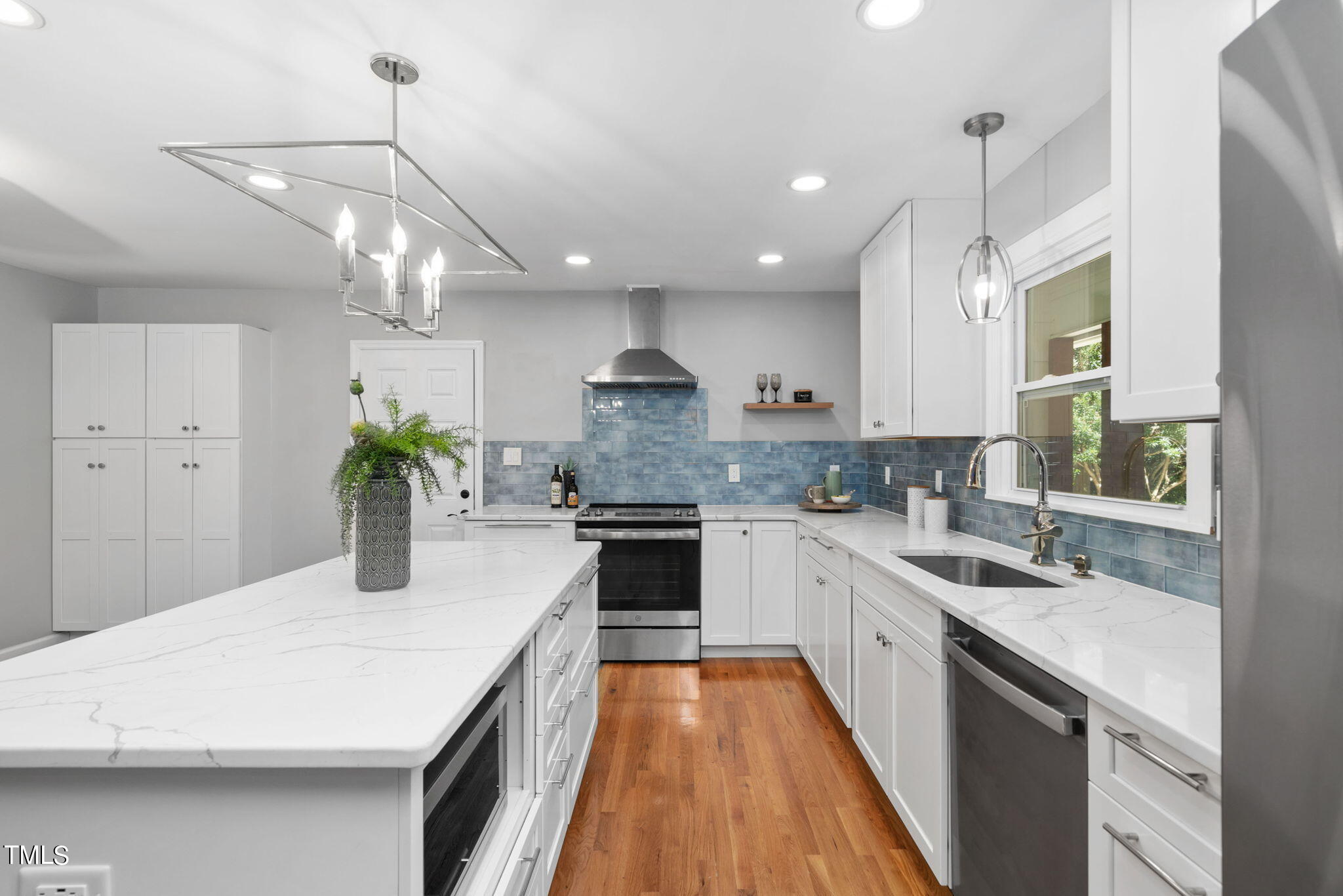 4817 Latimer Road Raleigh, NC 27609 - Photo 5 of 45 a kitchen with a white center island a sink stainless steel appliances and cabinets