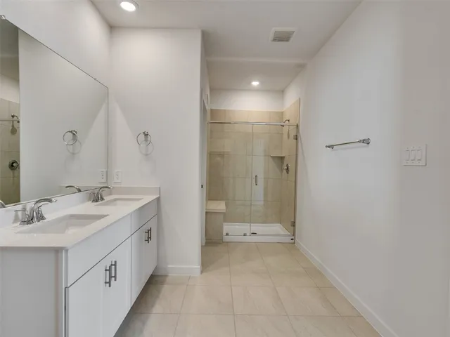 a bathroom with a double vanity sink a toilet and shower