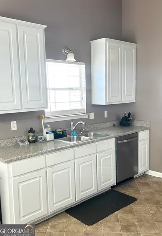 a kitchen with granite countertop white cabinets white appliances and a sink