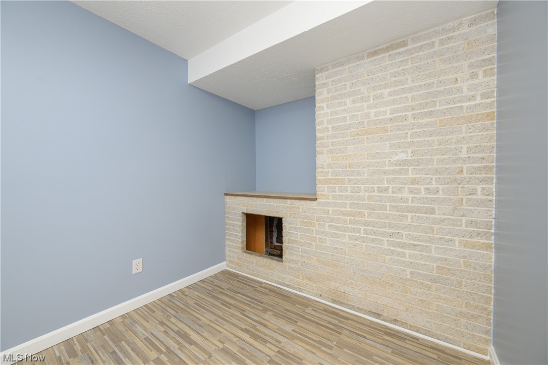 279 South Messner Road New Franklin, OH 44319 - Photo 19 of 30 Unfurnished living room featuring light hardwood / wood-style floors, a brick fireplace, and brick wall