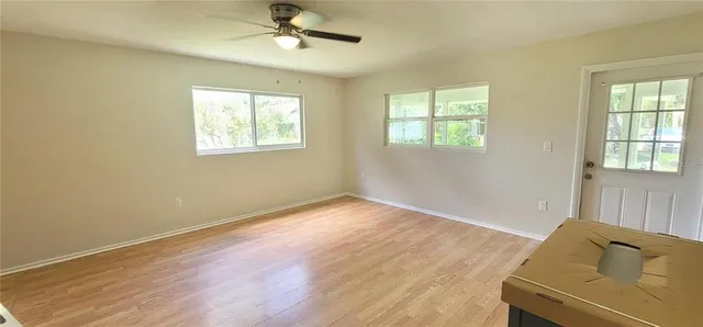 a view of empty room with wooden floor and fan