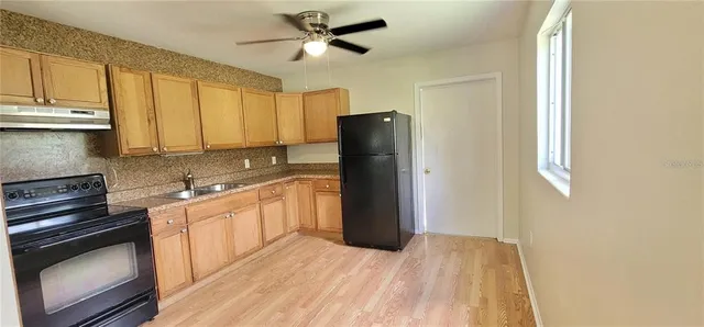 a kitchen with stainless steel appliances granite countertop a refrigerator a stove a sink and dishwasher with wooden floor