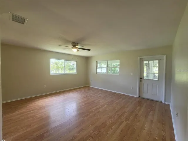 a view of an empty room with wooden floor and a window