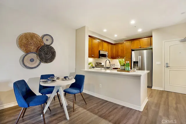 a kitchen with stainless steel appliances granite countertop a refrigerator a stove a sink and a dining table with wooden floor