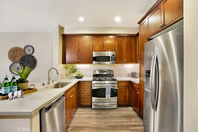 a kitchen with stainless steel appliances granite countertop a refrigerator a stove and a sink