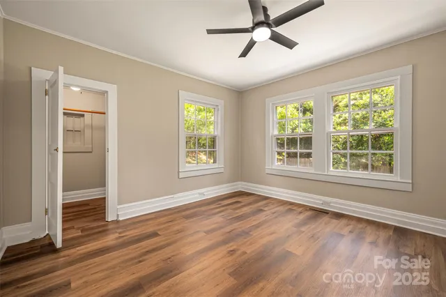 a view of empty room with wooden floor and fan