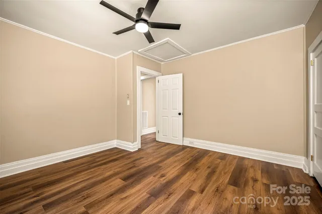 an empty room with wooden floor and a ceiling fan