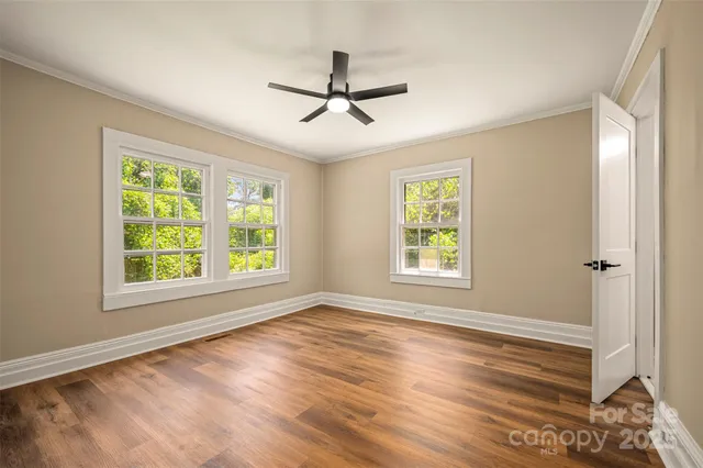 a view of empty room with wooden floor and fan