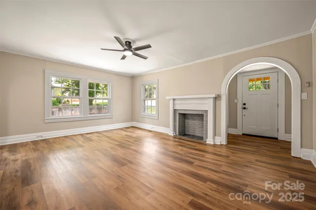 an empty room with windows fireplace and wooden floor