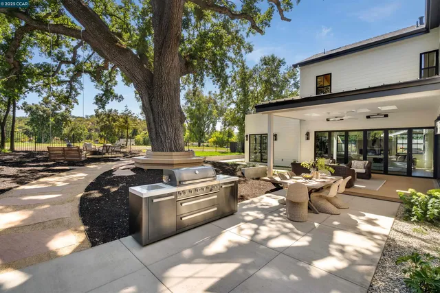 a view of a swimming pool with lawn chairs and large trees