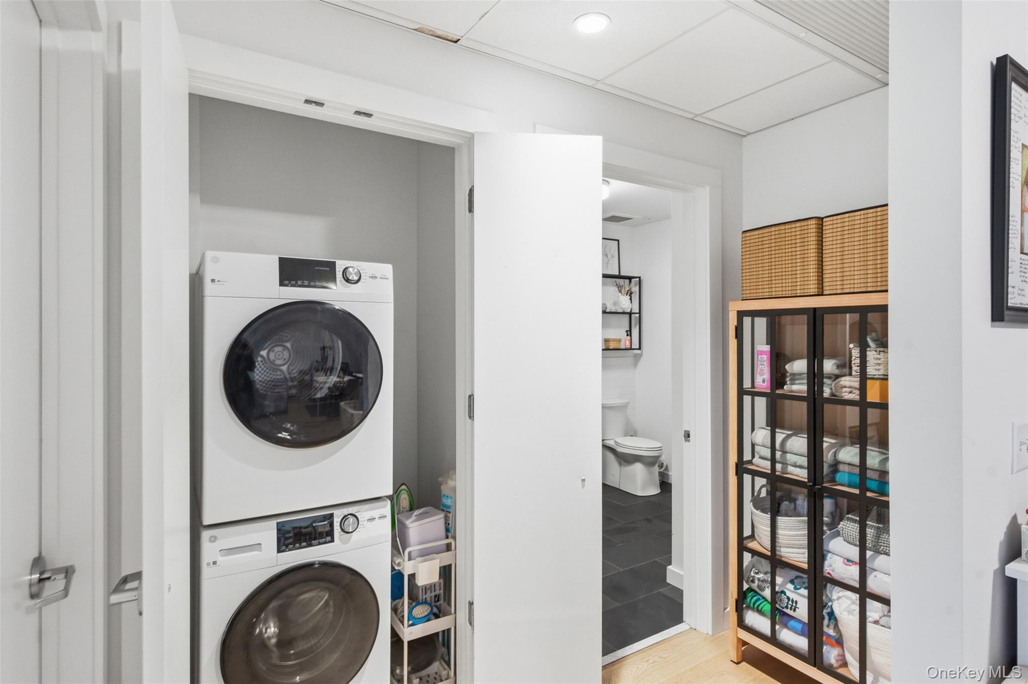 249 Main Street, Unit 305 Beacon, NY 12508 - Photo 18 of 36 Laundry room with stacked washer and clothes dryer, a drop ceiling, and light wood-style flooring