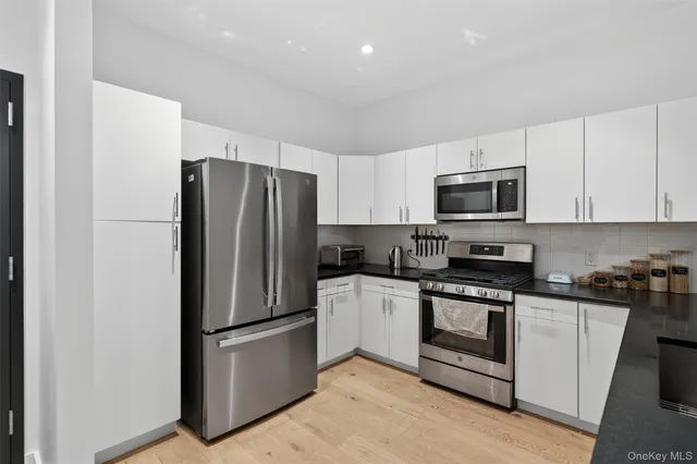 a kitchen with stainless steel appliances granite countertop a sink and white cabinets