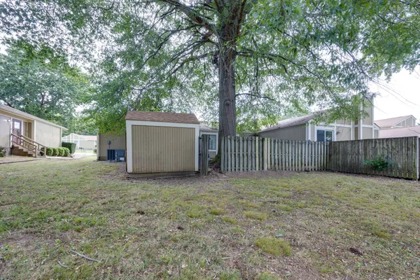 a view of a backyard with large trees and wooden fence