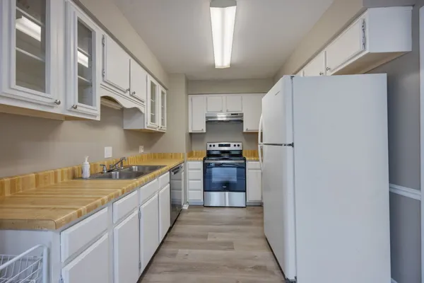 a kitchen with stainless steel appliances granite countertop a refrigerator a stove and a sink