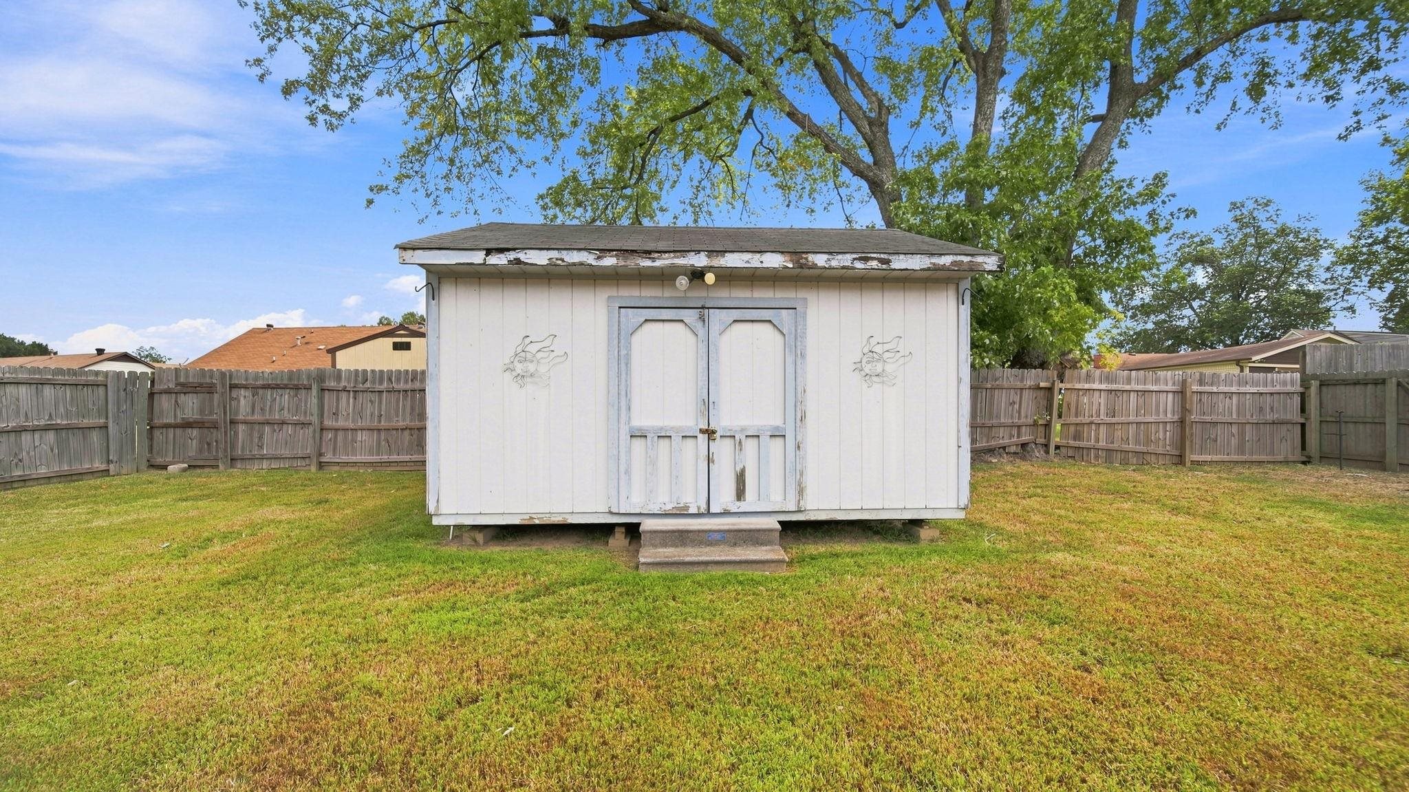 4920 Whitworth Road Memphis, TN 38116 - Photo 32 of 32 Expansive lawn featuring a storage shed with double doors and a wood fence enclosure