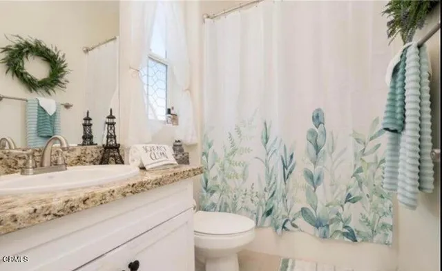 a bathroom with a granite countertop sink and a toilet